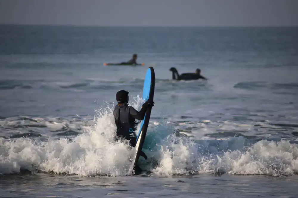 Instructor explicando la técnica de surf en la arena a los alumnos